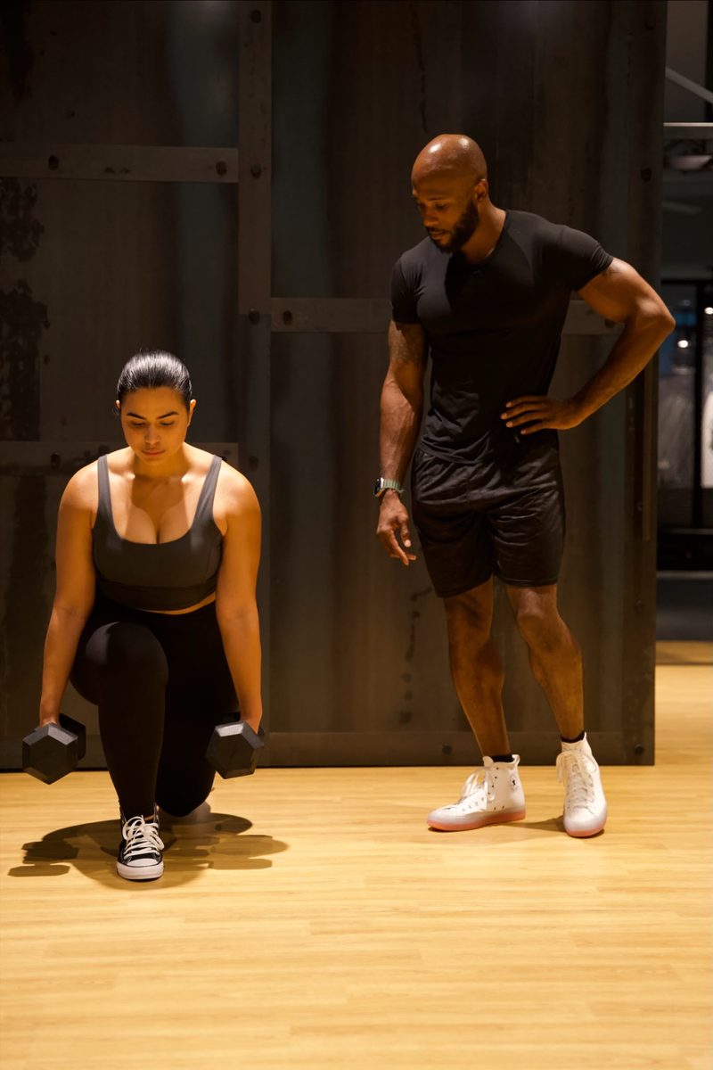 Coach Tae guiding a client through dumbbell lunges