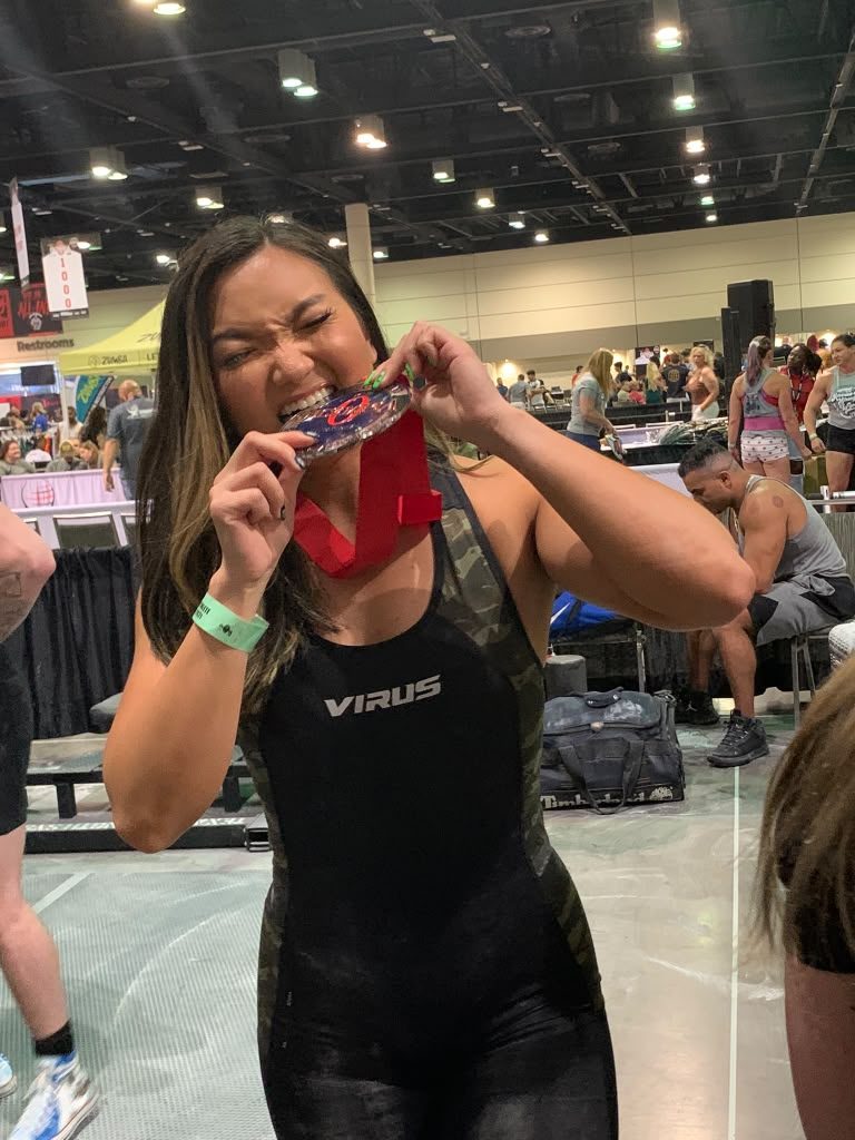 Client biting her medal after a powerlifting meet